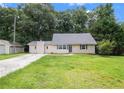 Exterior view of a cozy home with neutral siding, a well-manicured lawn, and a detached garage at 60 Newton Ridge Dr, Covington, GA 30014
