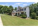 Charming two-story home with lush green lawn, accented by mature trees and neat shrubbery at 7090 River Island Cir, Buford, GA 30518
