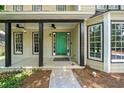 Inviting front porch with black columns, ceiling fans, and a pop of color from the bright green door at 5055 Southland Dr, Woodstock, GA 30188