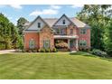 Charming two-story brick home with a welcoming front porch and lush greenery at 7125 Heard Rd, Cumming, GA 30041
