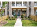 Townhome with a cozy porch, a yellow door adorned with wreaths, and manicured front yard landscaping at 579 Brashy St, Woodstock, GA 30188