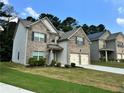 View of a brick and siding two-story home with a two-car garage and green lawn at 7487 Rudder Cir, Fairburn, GA 30213