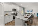 Well-lit kitchen features white cabinets, stainless steel appliances, and a spacious island with seating at 4944 Jatoba Rd, Acworth, GA 30101