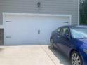 Attached two car garage with a clean white door and a blue car parked on the driveway at 4480 Merrigold Way, Fairburn, GA 30213