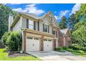Angle view of charming two-story home featuring a brick and siding exterior, well-manicured lawn, and an attached two-car garage at 3117 Blowing Wind Nw Ct, Acworth, GA 30101