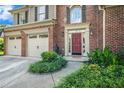 A beautiful brick home featuring a red door, green shrubs, and a two-car garage at 3117 Blowing Wind Nw Ct, Acworth, GA 30101