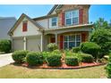 Close up of the front facade, colorful plants and a manicured lawn at 574 Friars Head Dr, Suwanee, GA 30024