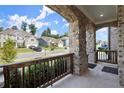 Covered front porch showing brick supports and dark wooden railing, with a view of a quiet street at 7410 Ansley View Ln, Cumming, GA 30028