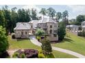 Stone home with manicured front lawn, mature trees, and circular driveway at 9695 Almaviva Dr, Alpharetta, GA 30022