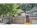 Charming townhouse featuring a two-car garage, brick accents, and mature trees at 109 Creighton Ln, Marietta, GA 30008