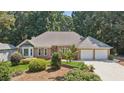 Charming brick home with a well-manicured lawn and a two-car garage nestled amongst mature trees at 5195 Overbend Trl, Suwanee, GA 30024