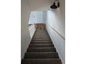Carpeted stairs with white railings lead to the upper level of the home, featuring a modern light fixture at 3120 Chattahoochee Rd, Cumming, GA 30041