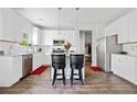 Modern kitchen with white cabinets, stainless steel appliances, granite countertops, and bar stool seating at 5780 Winding Lakes Dr, Cumming, GA 30028