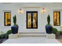 Stylish entryway featuring black double doors, sleek sconces, and modern planters on a white brick facade at 6090 River Chase Cir, Atlanta, GA 30328