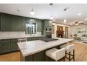 Open kitchen with an island, olive green cabinets, marble countertops and stainless steel appliances at 3089 Ranlo Dr, Atlanta, GA 30340