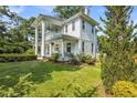 Charming two-story white home featuring a spacious lawn, front porch, and manicured landscaping at 205 Cobb St, Palmetto, GA 30268