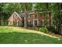 Traditional brick home with lush lawn, mature trees, black shutters, and a welcoming front entrance at 4971 Fairhaven Ne Way, Roswell, GA 30075