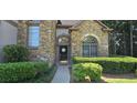 Close-up of home's front door with stone facade and decorative arched windows and manicured shrubs at 3310 Mcclure Woods Ct, Duluth, GA 30096