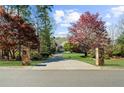 Long paved driveway leading to a grand home, flanked by mature trees and stone pillars, with well-manicured lawn at 1525 Lockridge Dr, Cumming, GA 30041