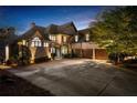 An evening shot of the home's exterior with landscape lighting showcasing the three-car garage and paved driveway at 1525 Lockridge Dr, Cumming, GA 30041
