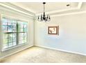 Bright, carpeted dining room with a large window and elegant chandelier, perfect for Gathering meals at 5599 Wheeler Ridge Rd, Auburn, GA 30011