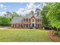 Stately two-story brick home featuring a well-manicured lawn and mature trees at 730 Mount Oglethorpe Trl, Alpharetta, GA 30022