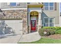 Inviting home exterior featuring a stone facade, red front door with wreath, and well-maintained landscaping at 2325 Lake Cove Ct, Buford, GA 30519
