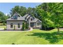 Two story home with stone and neutral tone siding surrounded by green trees at 619 Lovinggood Trl, Woodstock, GA 30189