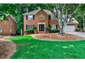 Beautiful brick home featuring manicured lawn, shade trees, and an attached garage at 10575 Tuxford Dr, Alpharetta, GA 30022