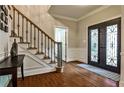 Welcoming foyer features hardwood floors, wrought iron staircase, and decorative front door at 10575 Tuxford Dr, Alpharetta, GA 30022