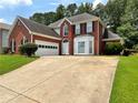 Charming two-story red brick home with a well-manicured lawn and a curved driveway at 134 Carolinas Way, Fayetteville, GA 30215
