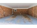 Spacious brick carport featuring a painted concrete floor and access door at 4077 Phils Ct, Tucker, GA 30084