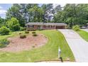 Brick home with an extended driveway and expansive front yard with mature trees at 4077 Phils Ct, Tucker, GA 30084