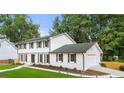 Spacious two-story home with white brick, dark shutters, and a neatly landscaped yard and an attached garage at 4555 Holliston Rd, Dunwoody, GA 30360