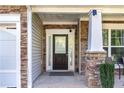 Close-up of a home's stone-accented front entrance with a dark wooden door and sidelight window at 2481 Southhaven Ln, Buford, GA 30519