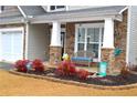 Inviting front porch with stone accents, a cozy bench, and well-maintained landscaping with colorful plants at 2481 Southhaven Ln, Buford, GA 30519
