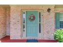 Close-up of a front door with decorative wreath, sidelights, and brick surround at 3370 Battlement Cir, Loganville, GA 30052