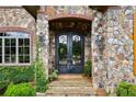 Elegant wrought-iron double doors framed by stone and brick, with mature landscaping at 4239 Lower Jersey Rd, Covington, GA 30014