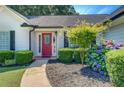 Close up of front entrance, with a red door and landscaped yard with flowering bushes at 2321 Sunnyview Ln, Dacula, GA 30019