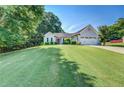 Well-maintained home with a manicured lawn, lush greenery, and a charming red front door at 2321 Sunnyview Ln, Dacula, GA 30019