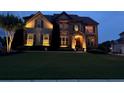 A nighttime view of a two-story home with beautiful landscaping and illuminated exterior at 4425 Martel Dr, Cumming, GA 30040