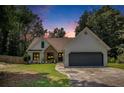 Charming home with a well-maintained lawn, stone accents, a gray two-car garage and lush landscaping at dusk at 2085 Castle Royale Dr, Lawrenceville, GA 30043