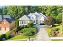 Manicured lawn and mature trees surround this beautiful two-story home with a neutral color scheme at 5059 Winding Hills Lane Ln, Woodstock, GA 30189