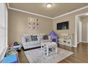 Cozy living room is shown with neutral colors, a sofa, table, TV, and play area at 1019 Avonley Creek Trce, Sugar Hill, GA 30518