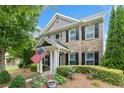 Charming brick home features manicured landscaping, covered entry, and an American flag for a welcoming curb appeal at 214 Harmony Lake Dr, Canton, GA 30115