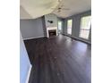 A spacious living room with a fireplace, dark vinyl floors, and natural light from large windows at 1 Thorntree Pass, Powder Springs, GA 30127