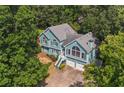 High-angle shot showcases a well-kept home featuring a spacious two-car garage nestled among lush, mature trees at 533 Coolsprings Walk, Woodstock, GA 30188