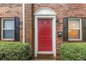 Up-close exterior view of the brick townhome entry, displaying a red door and neatly trimmed hedges at 115 Winding River Dr # B, Atlanta, GA 30350