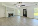 Cozy living room featuring a fireplace with brick surround, gray wood-look flooring, and a modern ceiling fan at 2335 Huntington Dr, Loganville, GA 30052