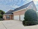 Side view of a brick home featuring an attached three-car garage and large driveway at 3580 Canon Creek Dr, Cumming, GA 30041